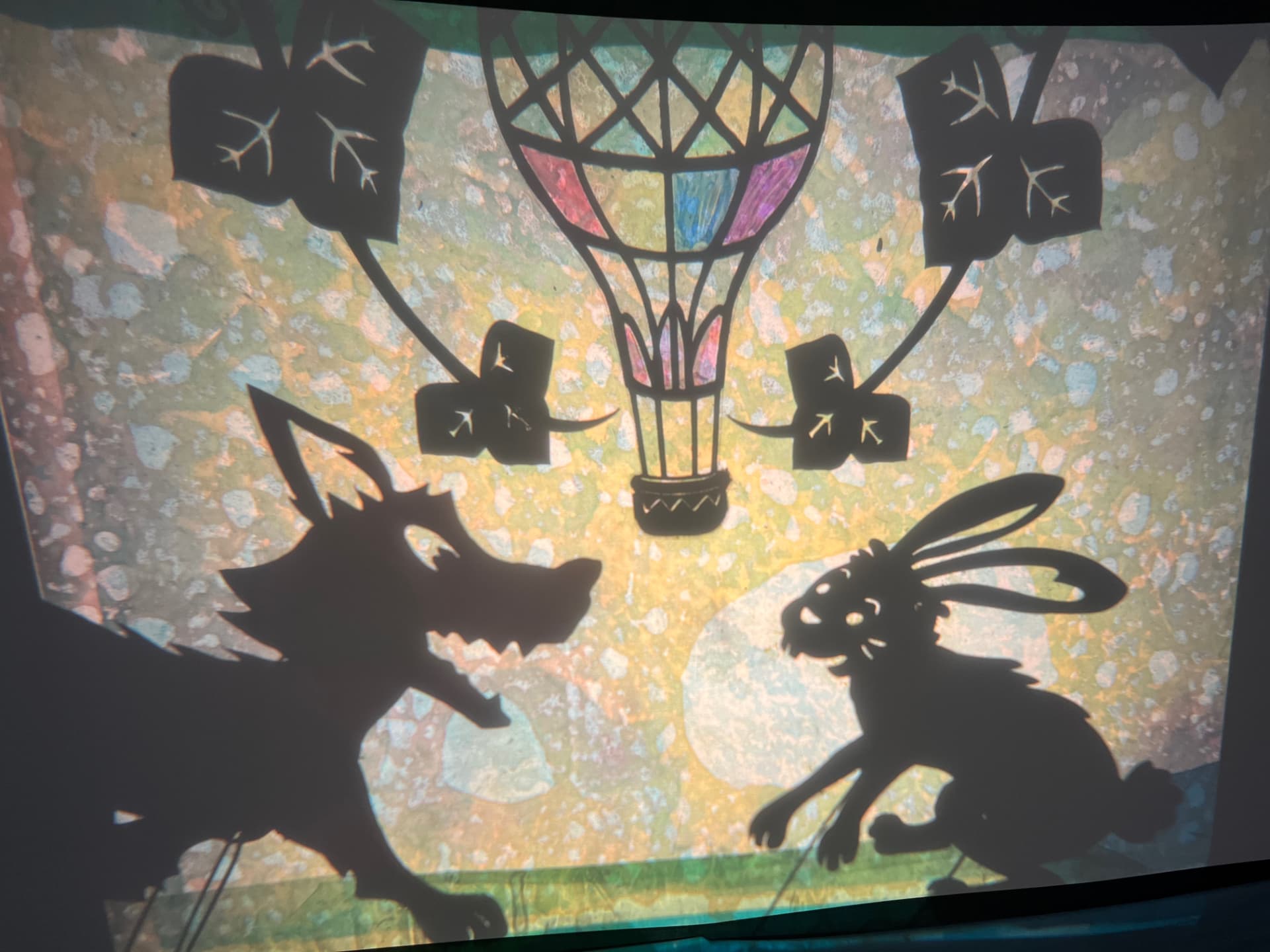 Shadow puppet wolf, rabbit and hot-air balloon glowing on the shadow screen